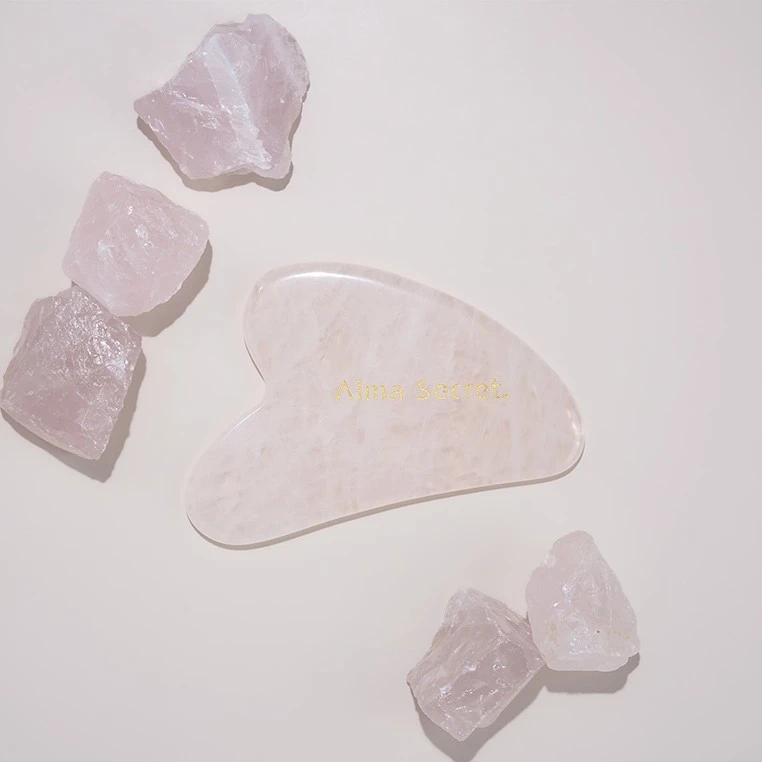 Facial Gua Sha Alma Secret piedra natural de masaje facial de cuarzo rosa.